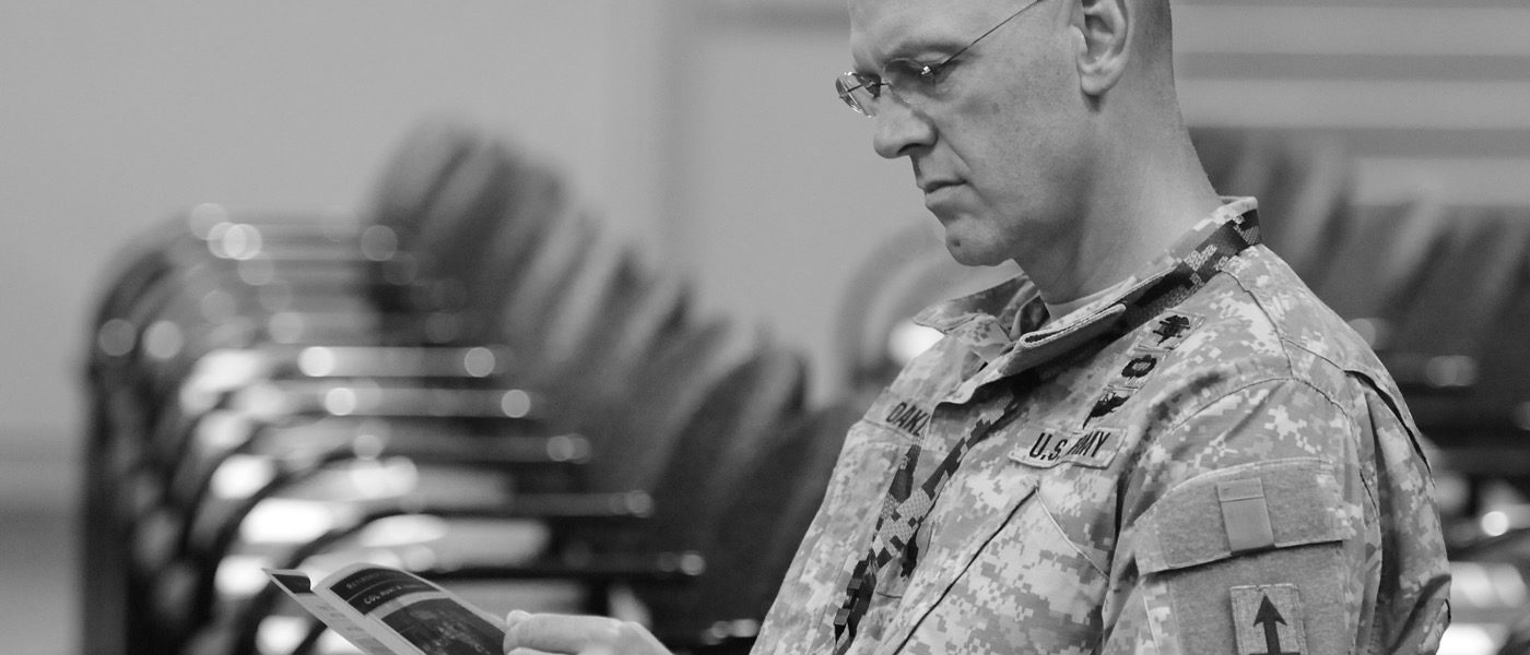 Active Duty Soldier reads a pamphlet at a retirement ceremony