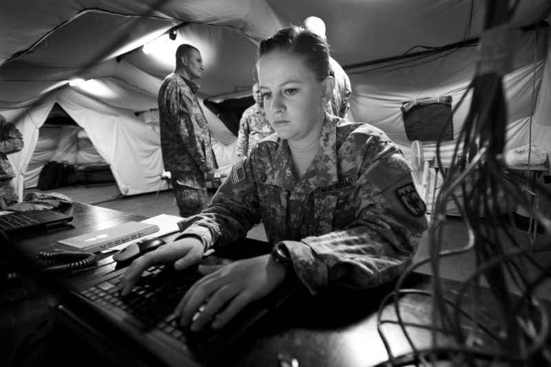 Military Woman working on her laptop in the field