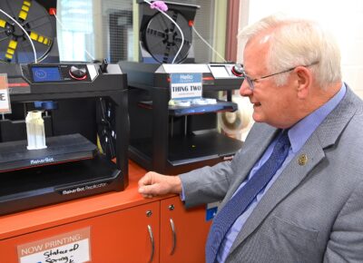 FTCC President Larry Keen looks at a 3 D printer printing a project