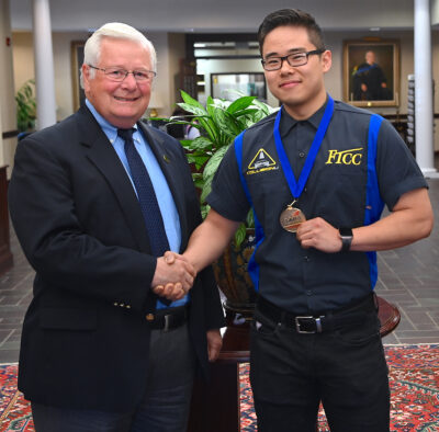 Dr. Larry Keen shakes hands with James Song, who is wearing his first place medal.
