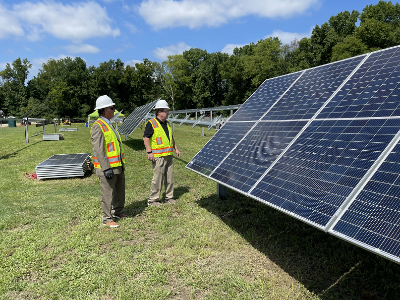 Two men look at a large solar array.