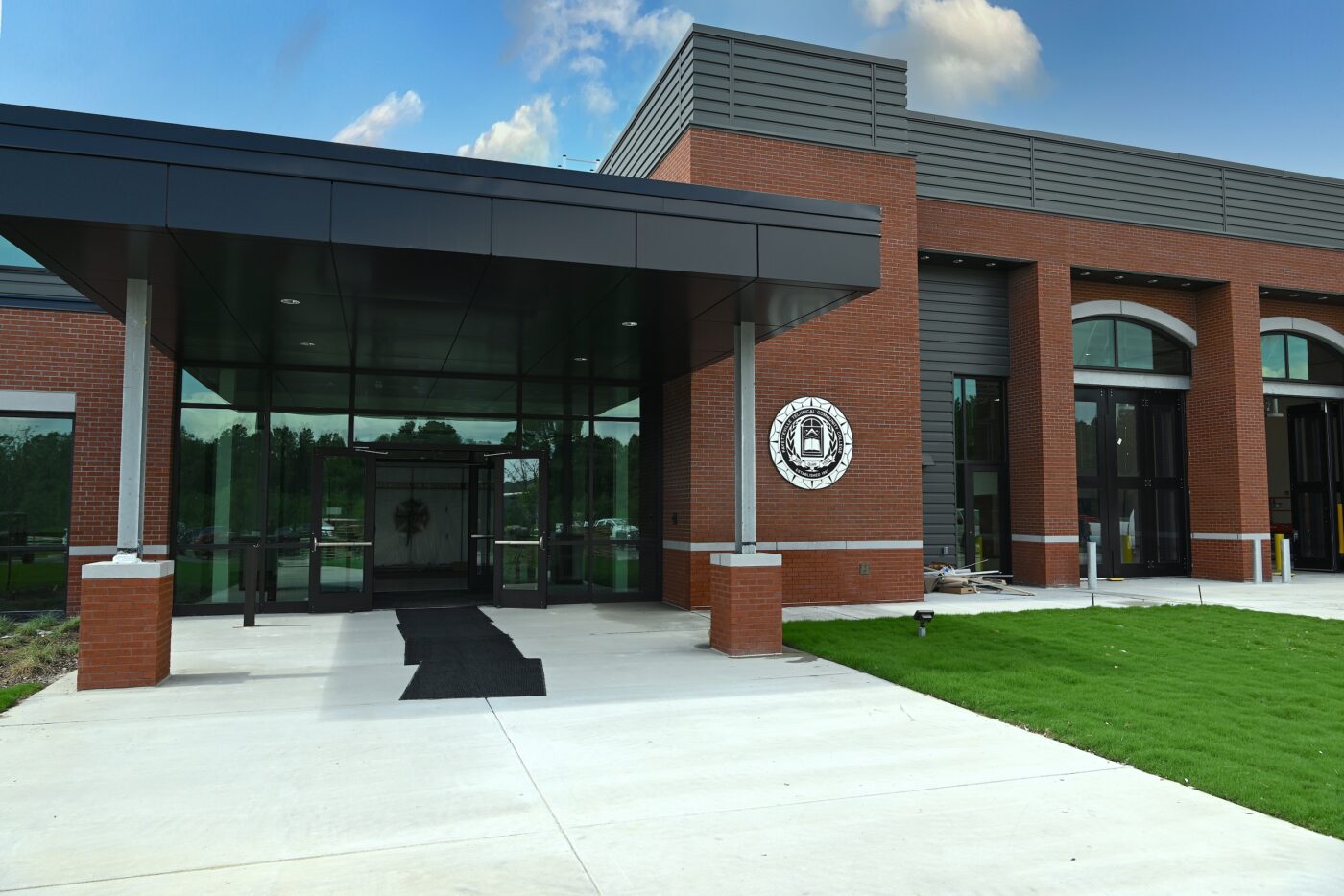 Entryway to a brick and black steel building with the FTCC seal on the wall.