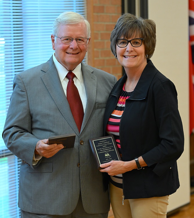 Larry Keen and Amy Cannon stand next to each other holding plaques.