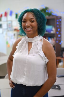 Shayla Battle, a 17-year-old girl with blue hair, stands with her hand on her hip smiling at the camera.