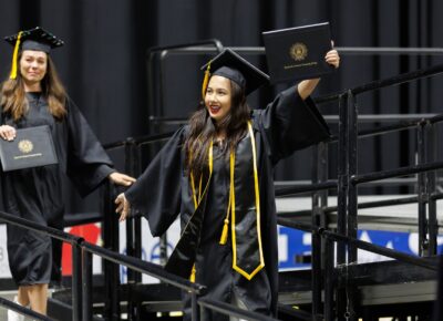 A graduate shows off her diploma folder to the crowd before exiting the stage.