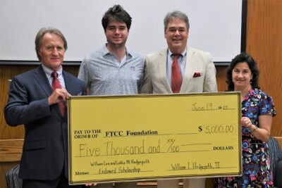 Four people hold a large ceremonial check.