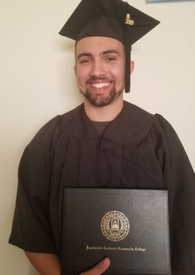 Brandon Little, photographed in 2019 in his cap and gown and holding his diploma folder