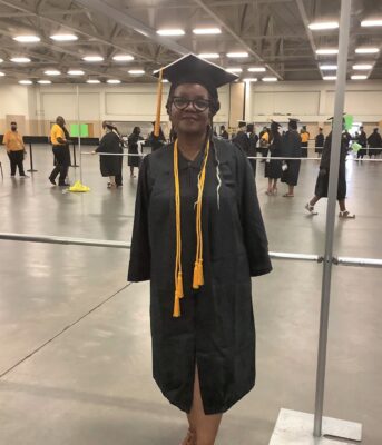 Gloriesrenea Stackhouse, dressed in a graduation cap and gown, stands in the staging area.