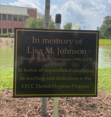 A black plaque with gold letters that say In memory of Lisa M. Johnson (Dental Hygiene Instructor 1998-2019) in honor of unparalleled excellence in teaching and dedication to the FTCC Dental Hygiene Program
