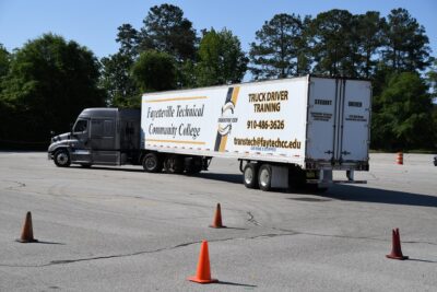 A truck with a trailer painted with Fayetteville Technical Community College branding on a training parking lot.