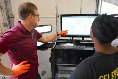 Instructor Tyler Manion points out diagnostics information on a computer screen to a student.