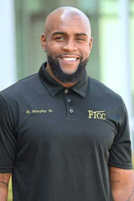 Ricardo Murphy, wearing a black FTCC polo, smiles at the camera.