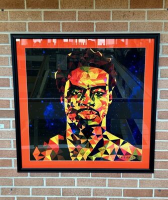 A photo of a framed digital illustration of a man created out of geometric shapes.
