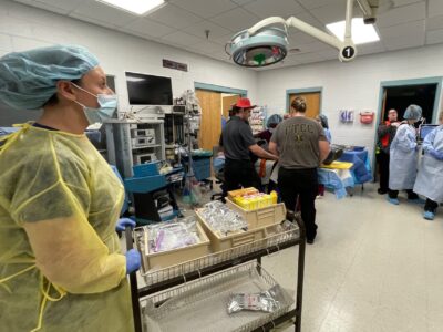 A student rolls a cart with medication on it into a classroom that is set up like an operating room in a mock trauma event.