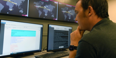 A student sits at a computer with monitors bn=