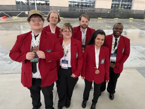 A group of people wearing red blazers stand together for a photo.