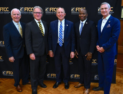 A group of five men wearing suits posing for a photo.