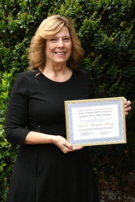 A woman holds a certificate while posing for a photo.