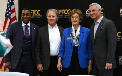 A group of three men and a woman in business attire pose for a photo.