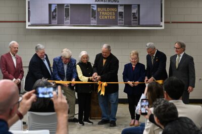 A group of people cut a gold ribbon in a ceremony.