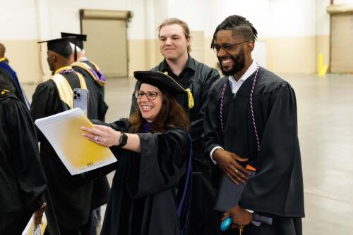 A-beaming-instructor-takes-a-selfie-with-two-smiling-graduates
