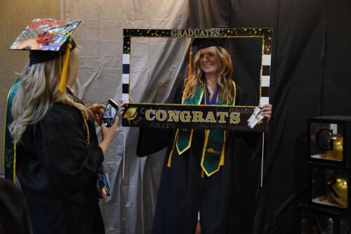 A-graduate-poses-for-a-photo-while-holding-a-congratulatory-frame