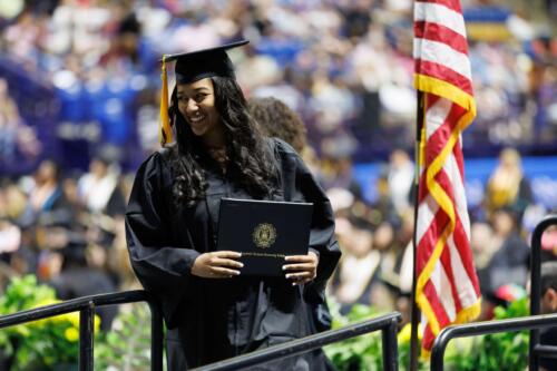 A-graduate-smiles-as-she-exits-the-stage-with-her-diploma