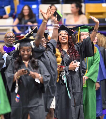 Two-graduates-lift-their-arms-and-grin-in-celebration-inside-the-Crown