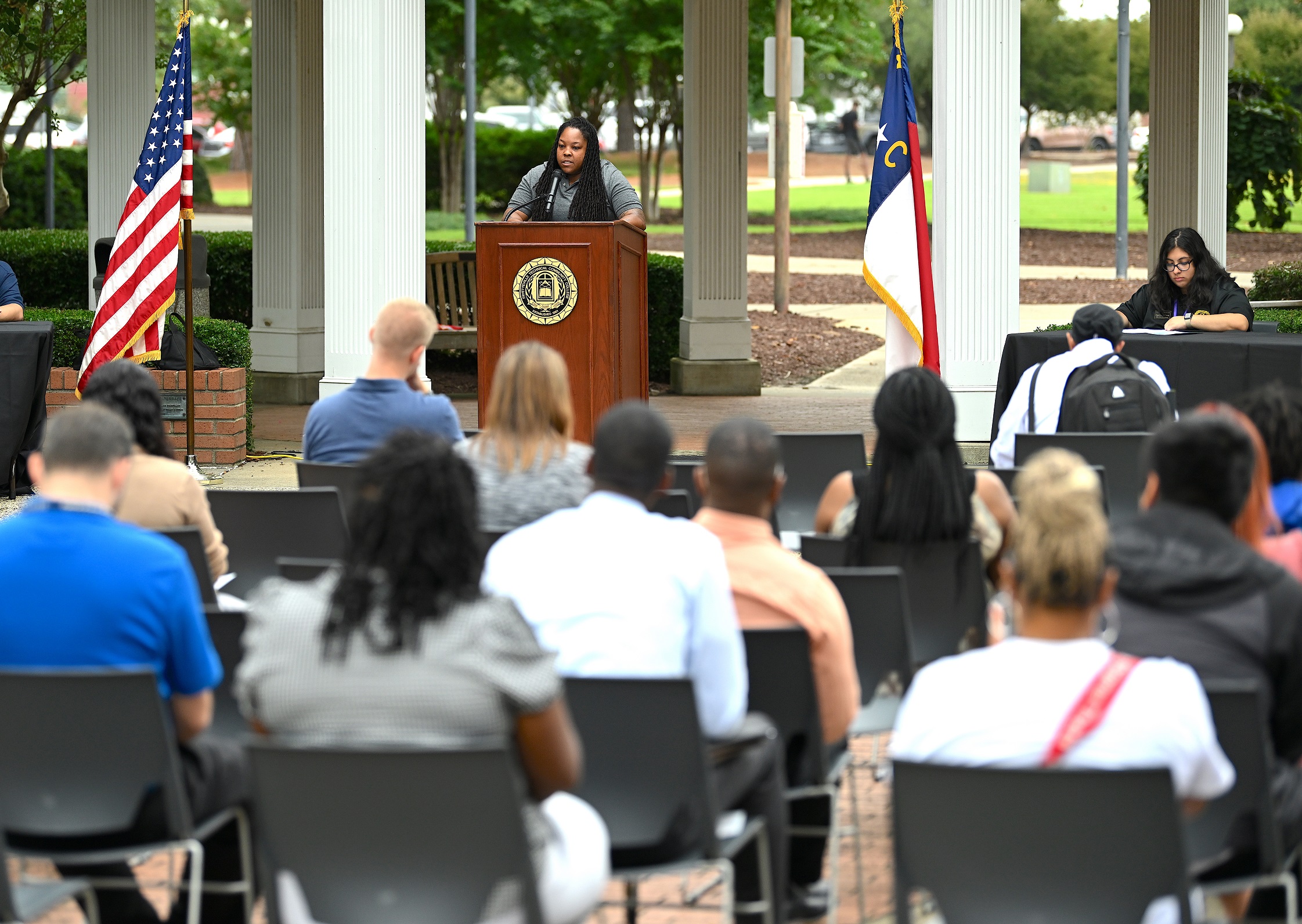 Chevonna Rose stands at the podium to speak. The back of the crowd is in the foreground.