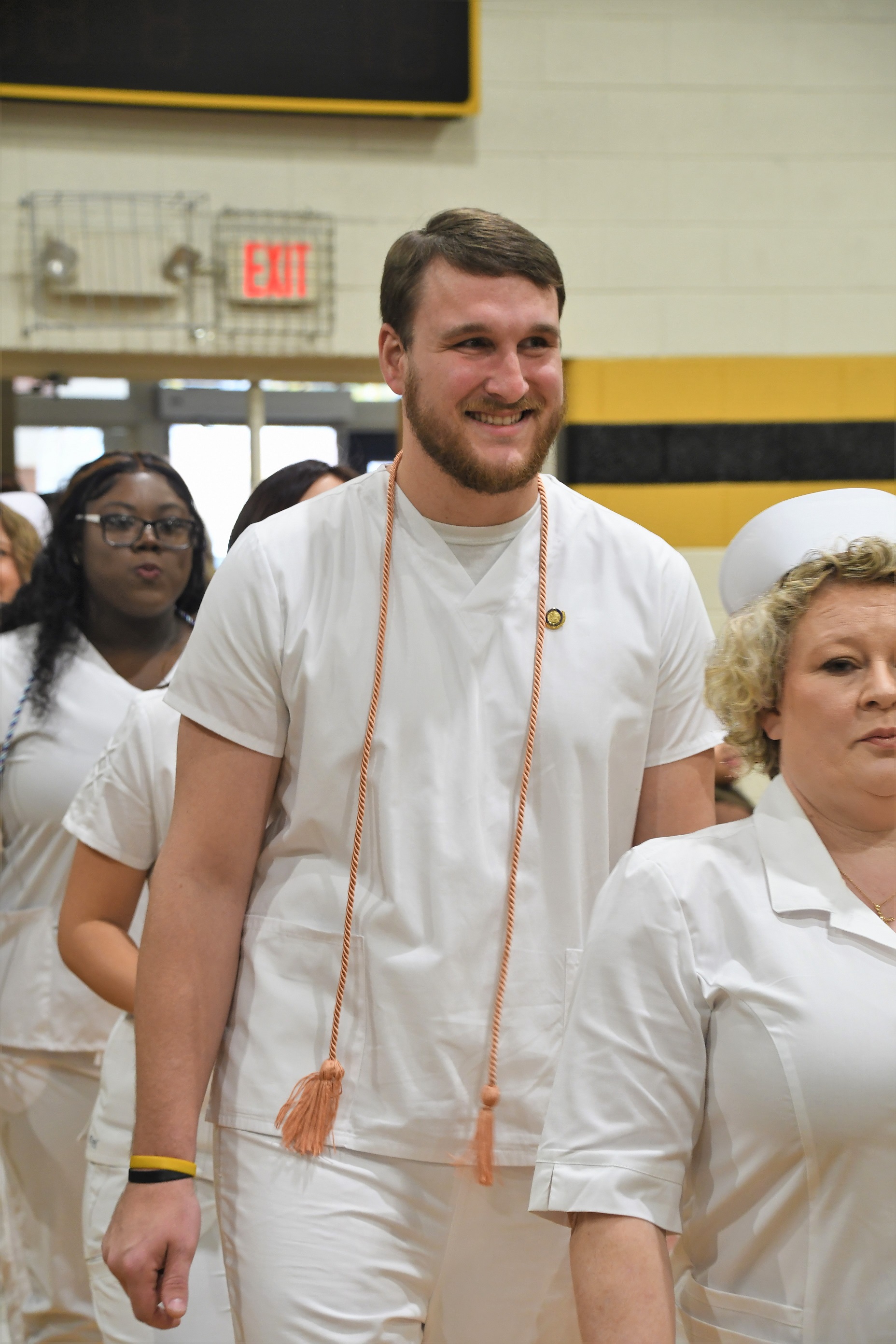 A tall male ADN graduate walks in the line to the pinning ceremony.