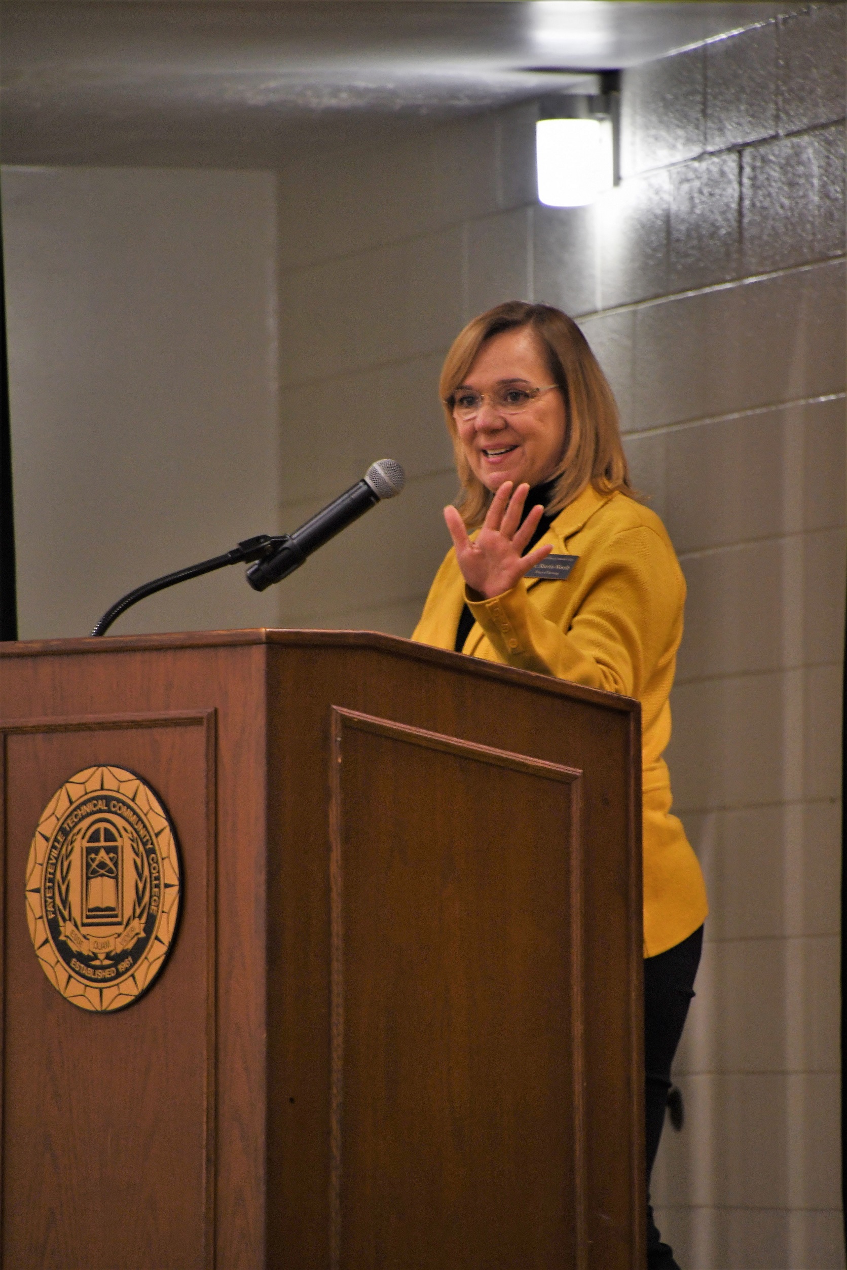 Dr. Murtis Worth, dressed in a gold blazer, speaks at the podium.