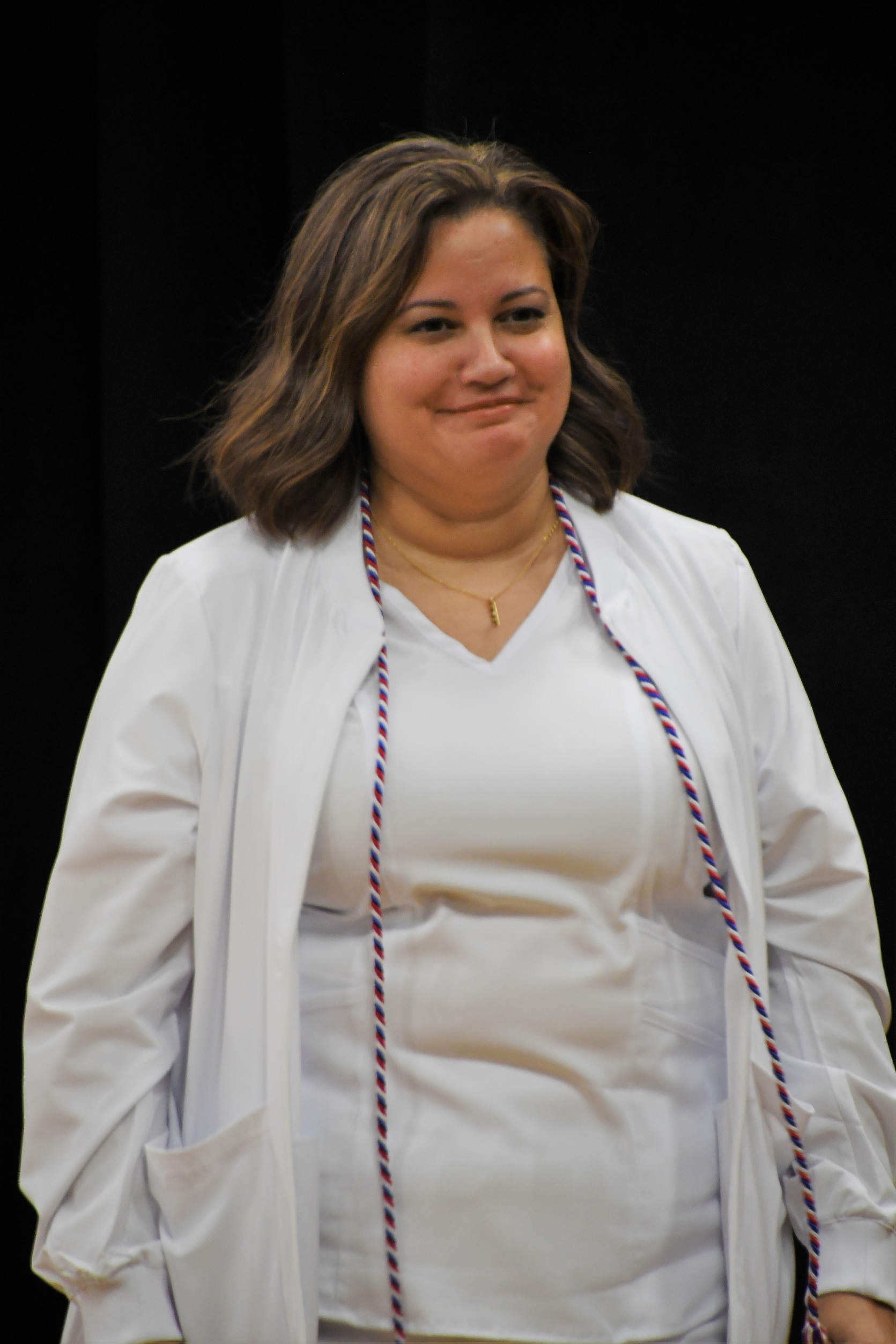 A graduate walks across the stage to receive her pin.