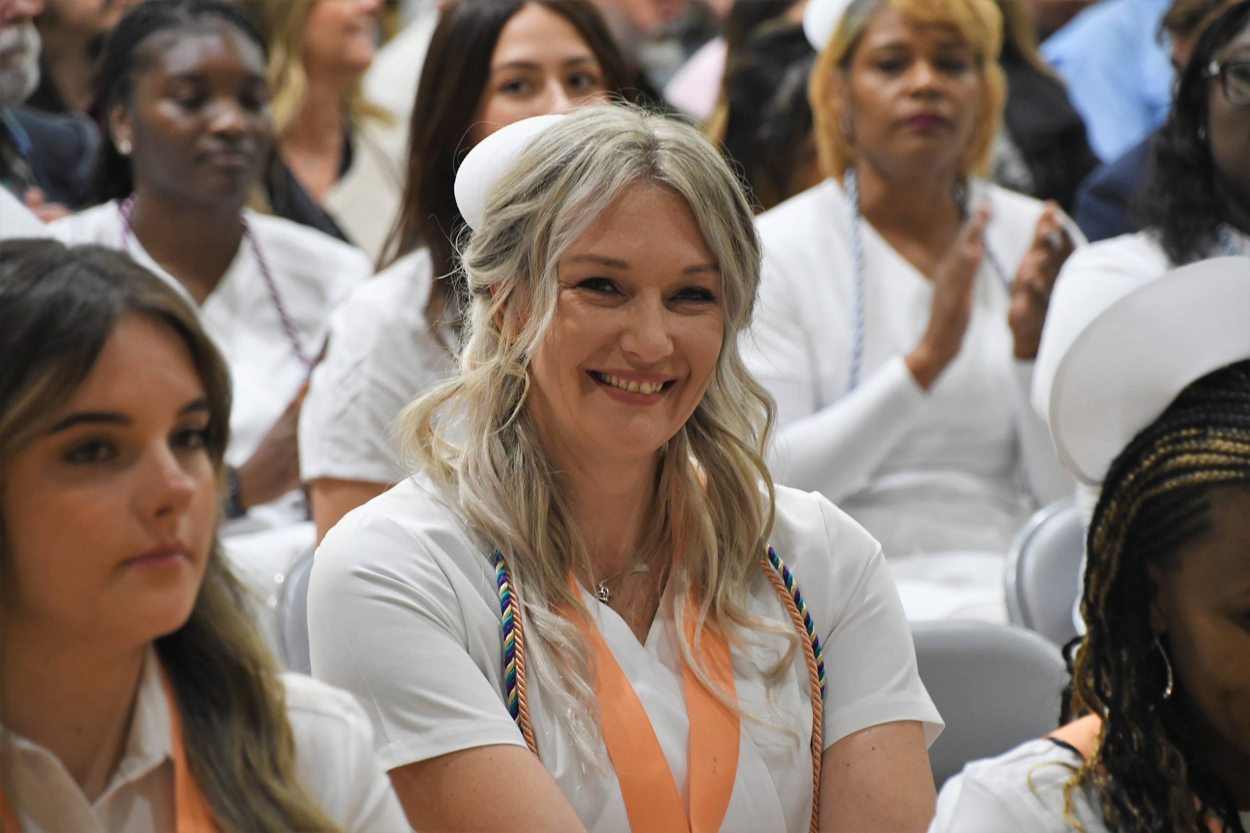 An close-up photo of a smiling ADN graduate seated in the audience after receiving her pin.