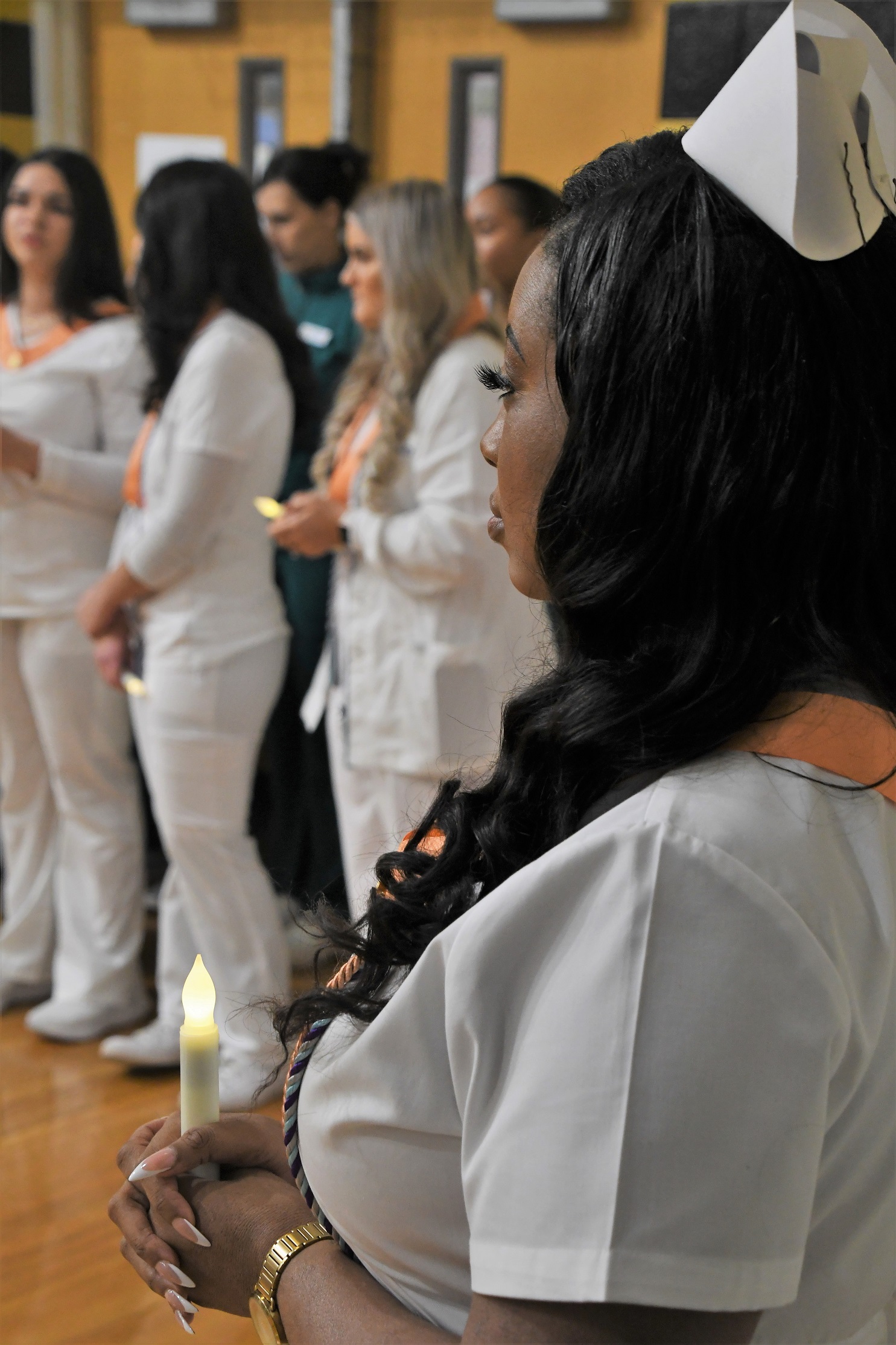 Graduates stand in a row holding glowing lamps.