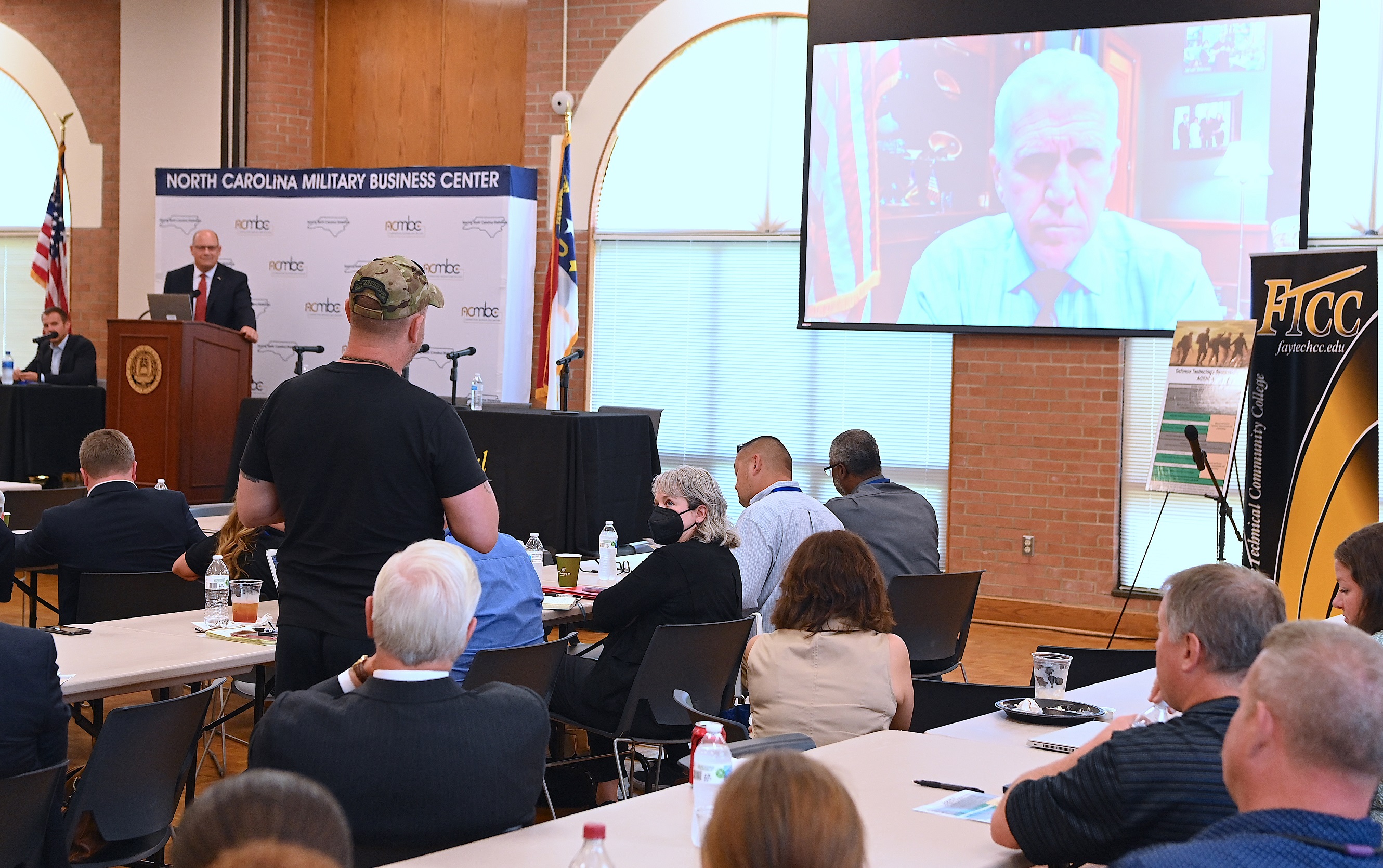 Sen. Thom Tillis appears on the video screen to address attendees at the Defense Technology Symposium.