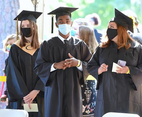 009 - Three graduates stand inside a tent