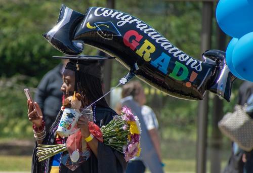 054 - A graduate looks at her phone