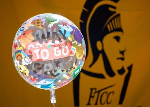 056 - A balloon congratulating graduates floats next to an FTCC tent