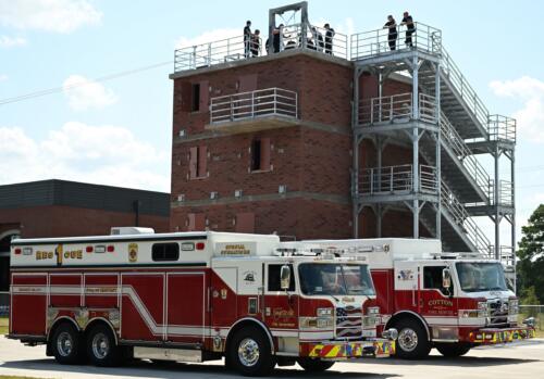 A photo of two fire trucks parked in front of a burn tower.