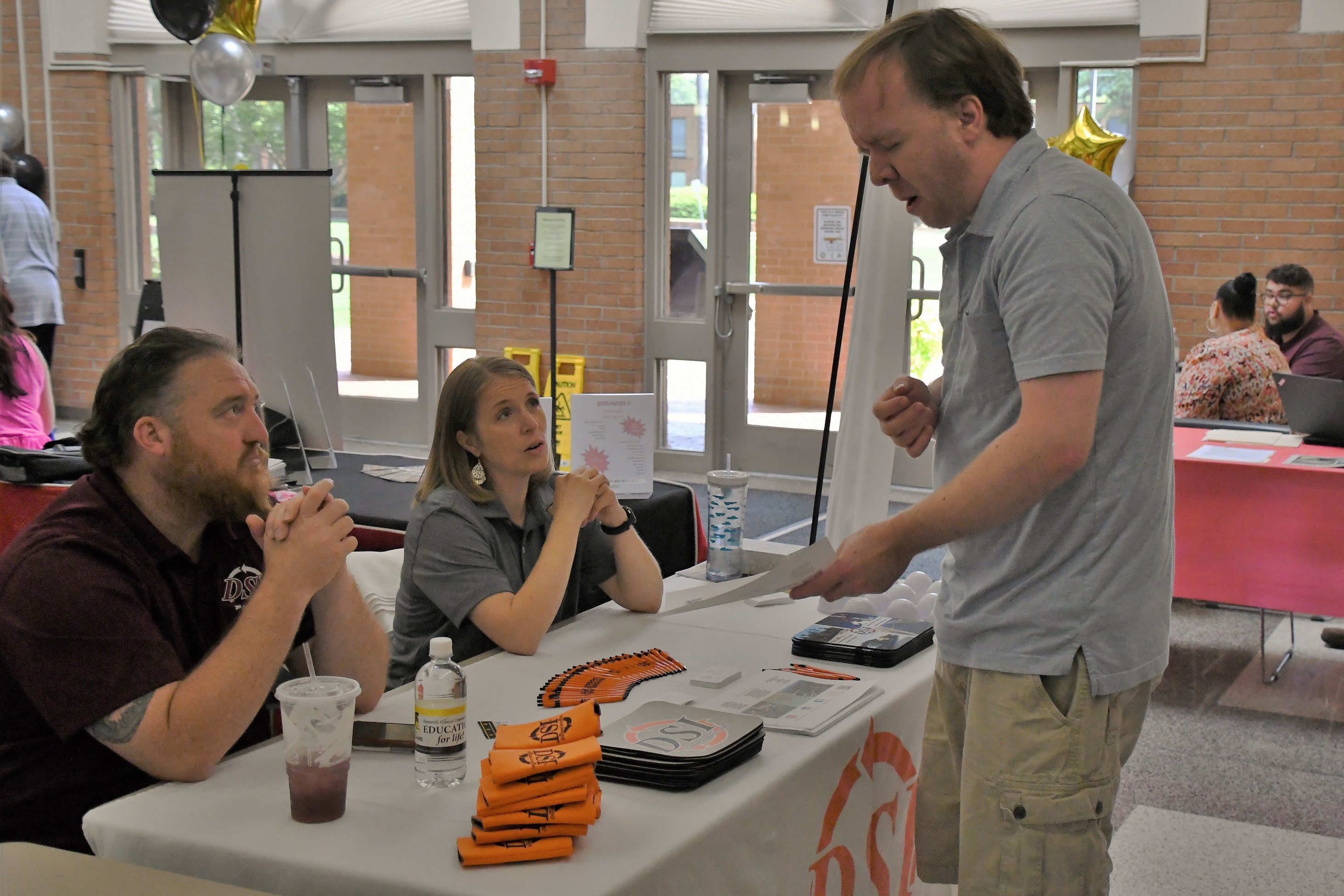 A man looks over a piece of paper at a table where two employers are sitting at the Expo.
