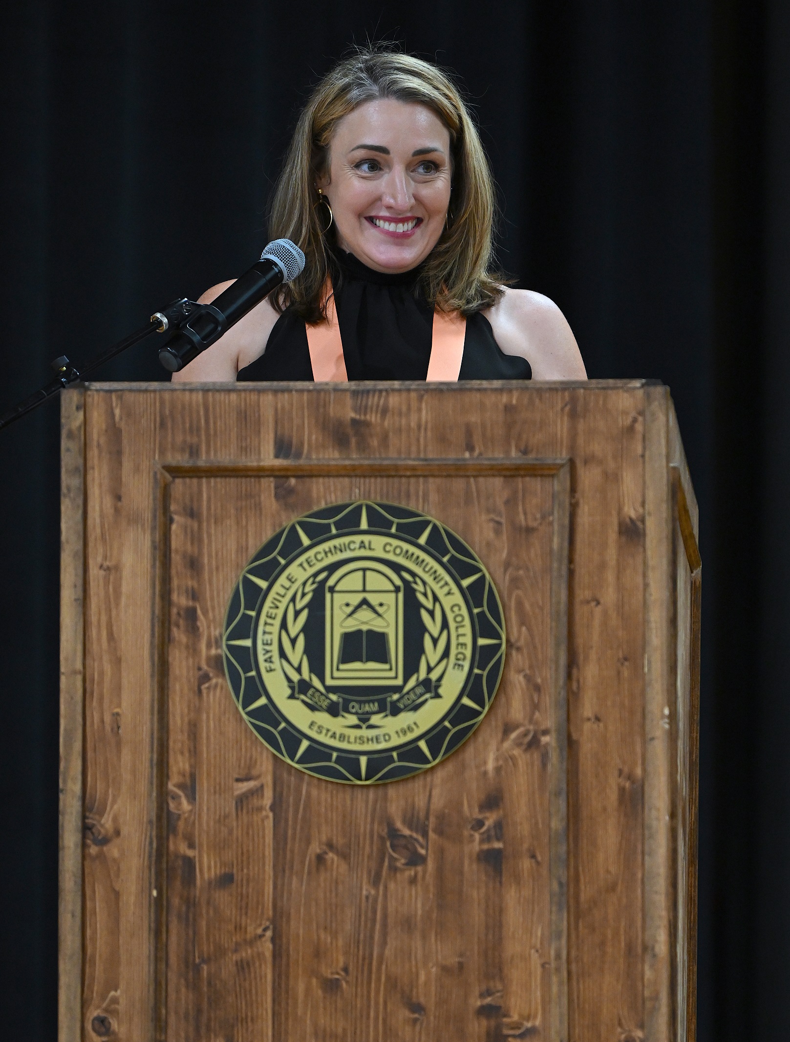 A close-up photo of Kari Lewis speaking at the podium.