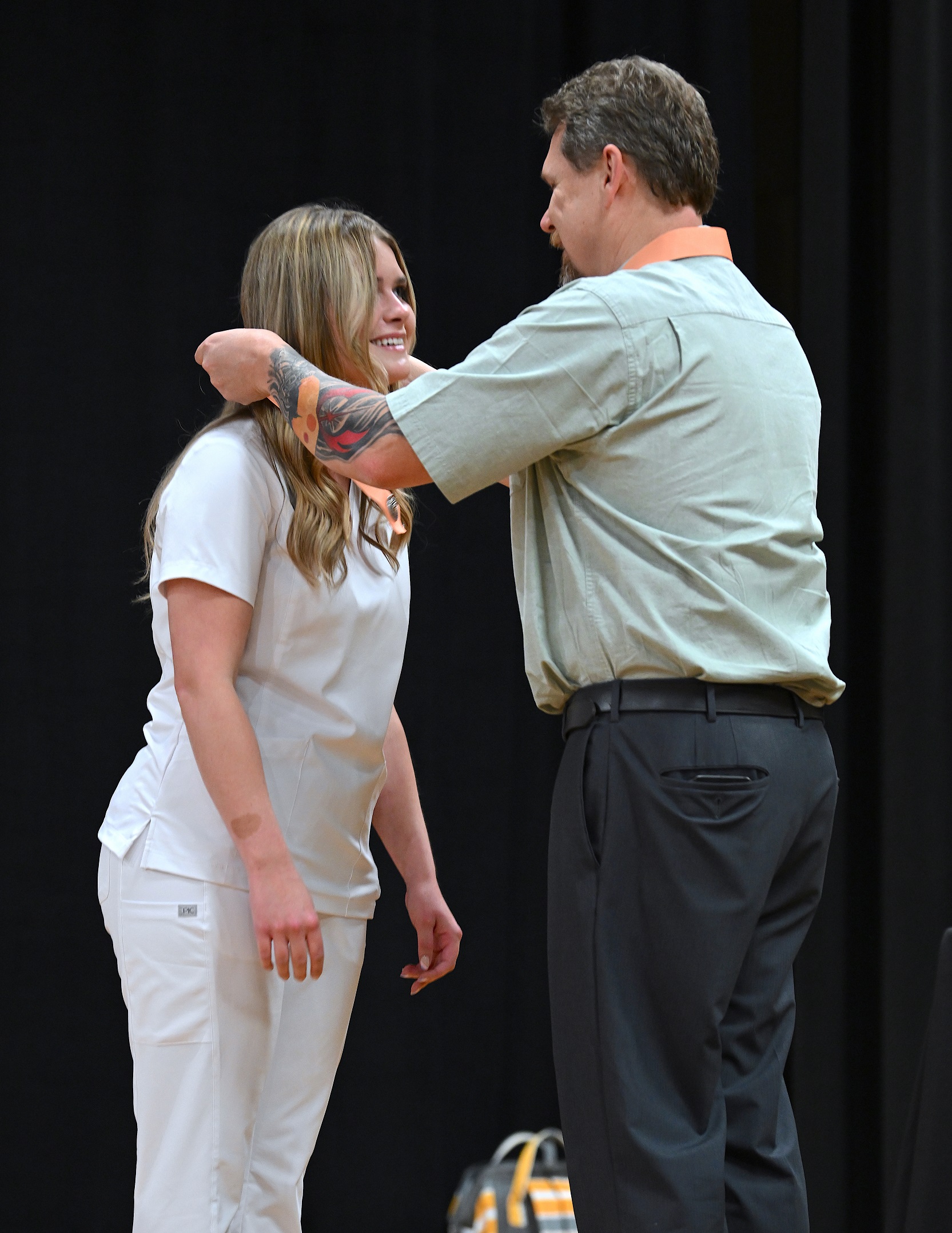 A graduate receives her pin, which is placed over her head by an instructor.