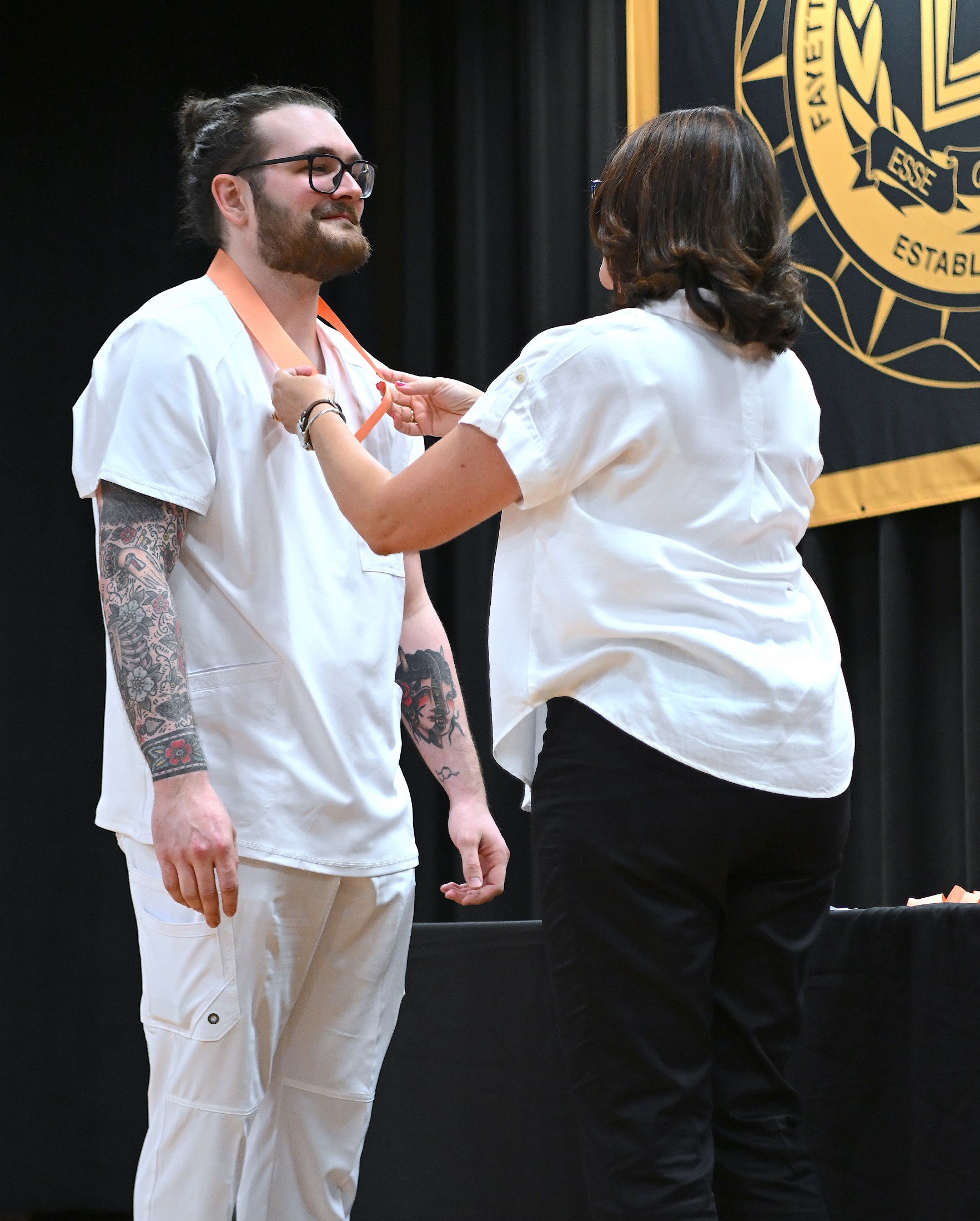 A graduate receives his pin from an instructor.