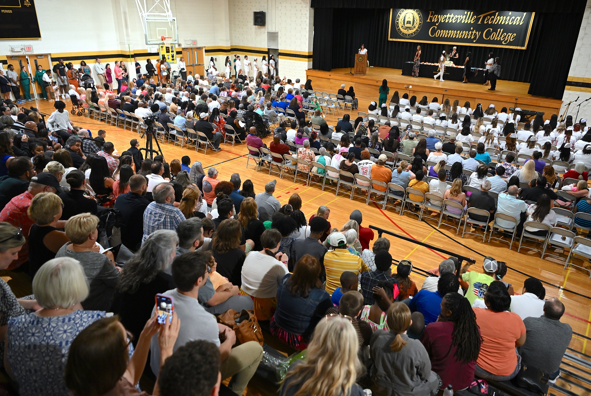 A wide photo of the audience shown from behind. The stage is visible in the background.