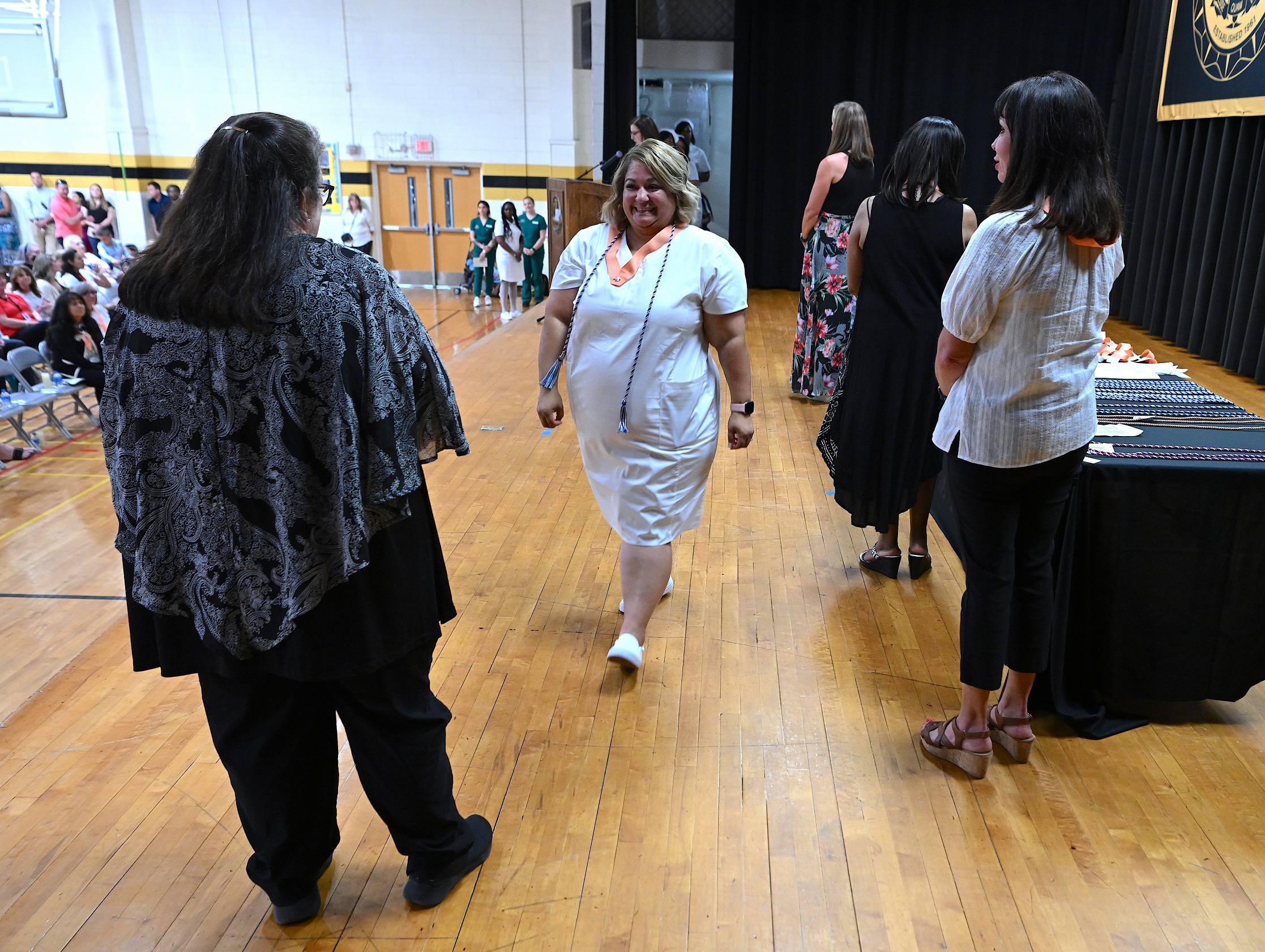 A graduate walks across the stage after receiving her pin.