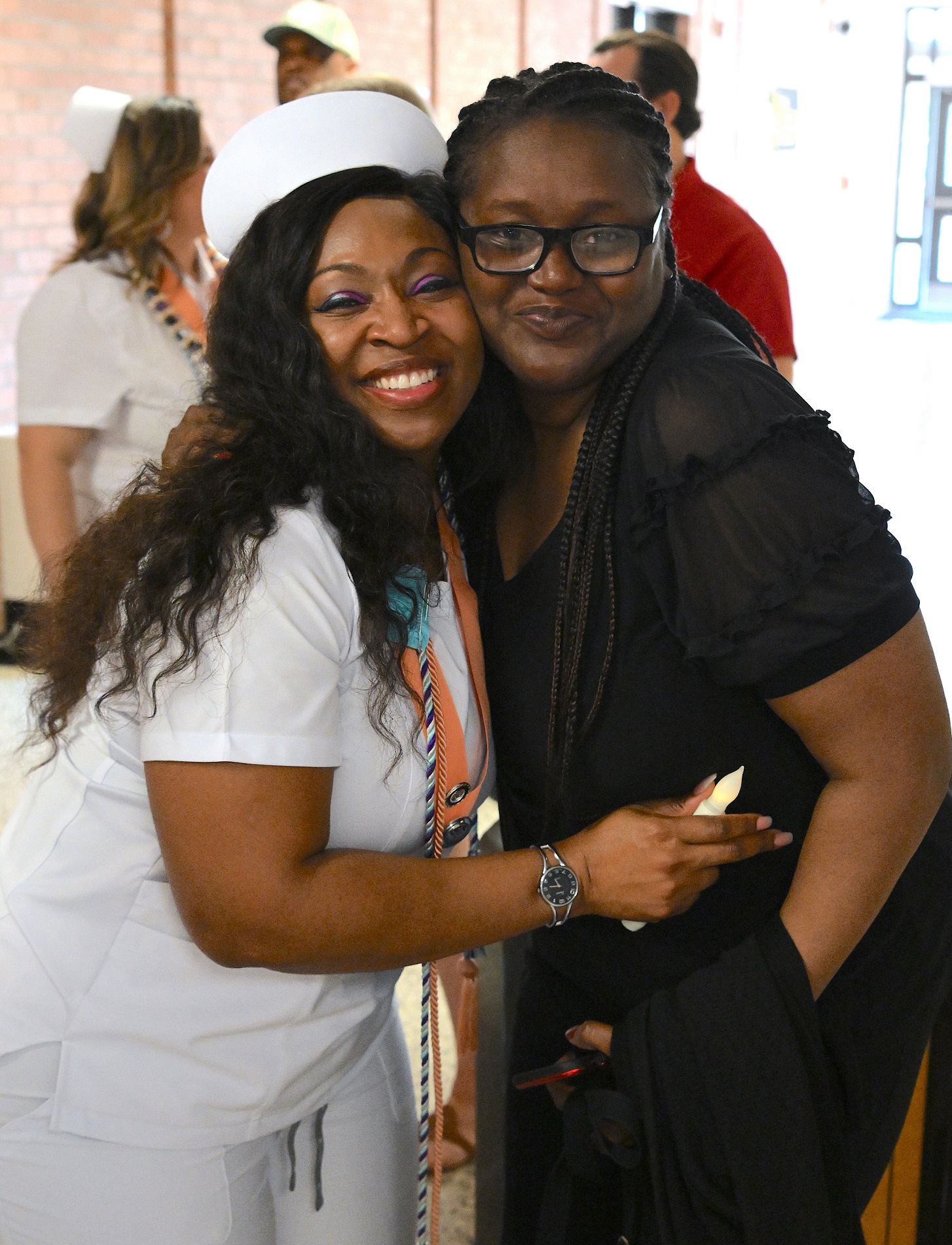 A graduate hugs a loved one and smiles at the camera.
