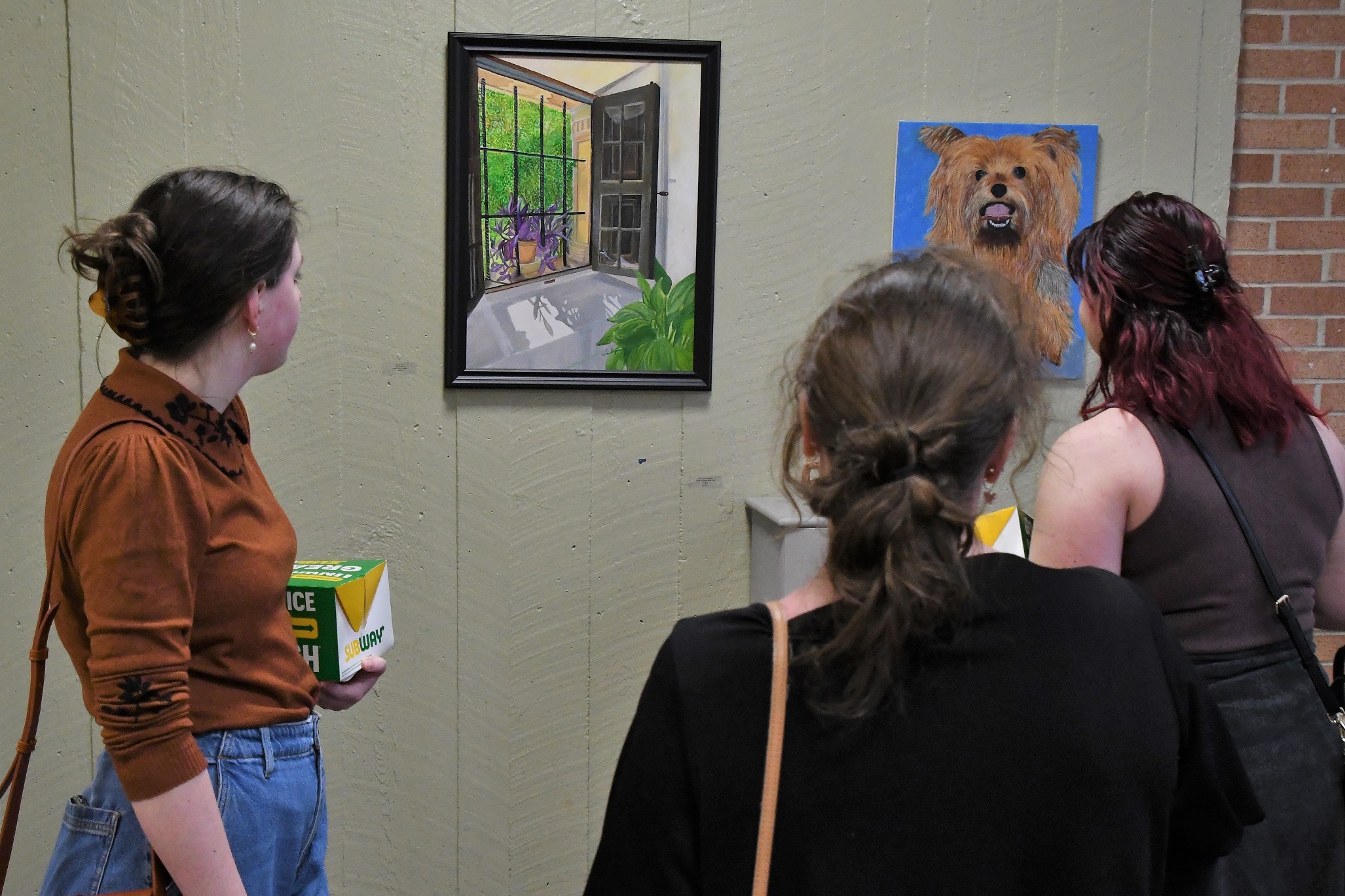 Visitors look at the two paintings hanging on the wall inside the library.