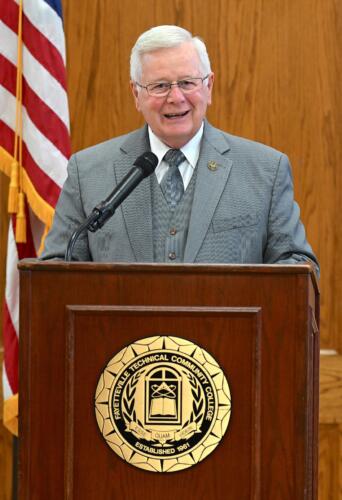 FTCC President Dr. J. Larry Keen, wearing a gray suit and tie, speaks at the podium at the BLET graduation.