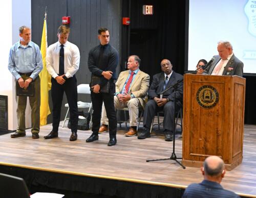 Three graduates stand on stage to receive individual awards.
