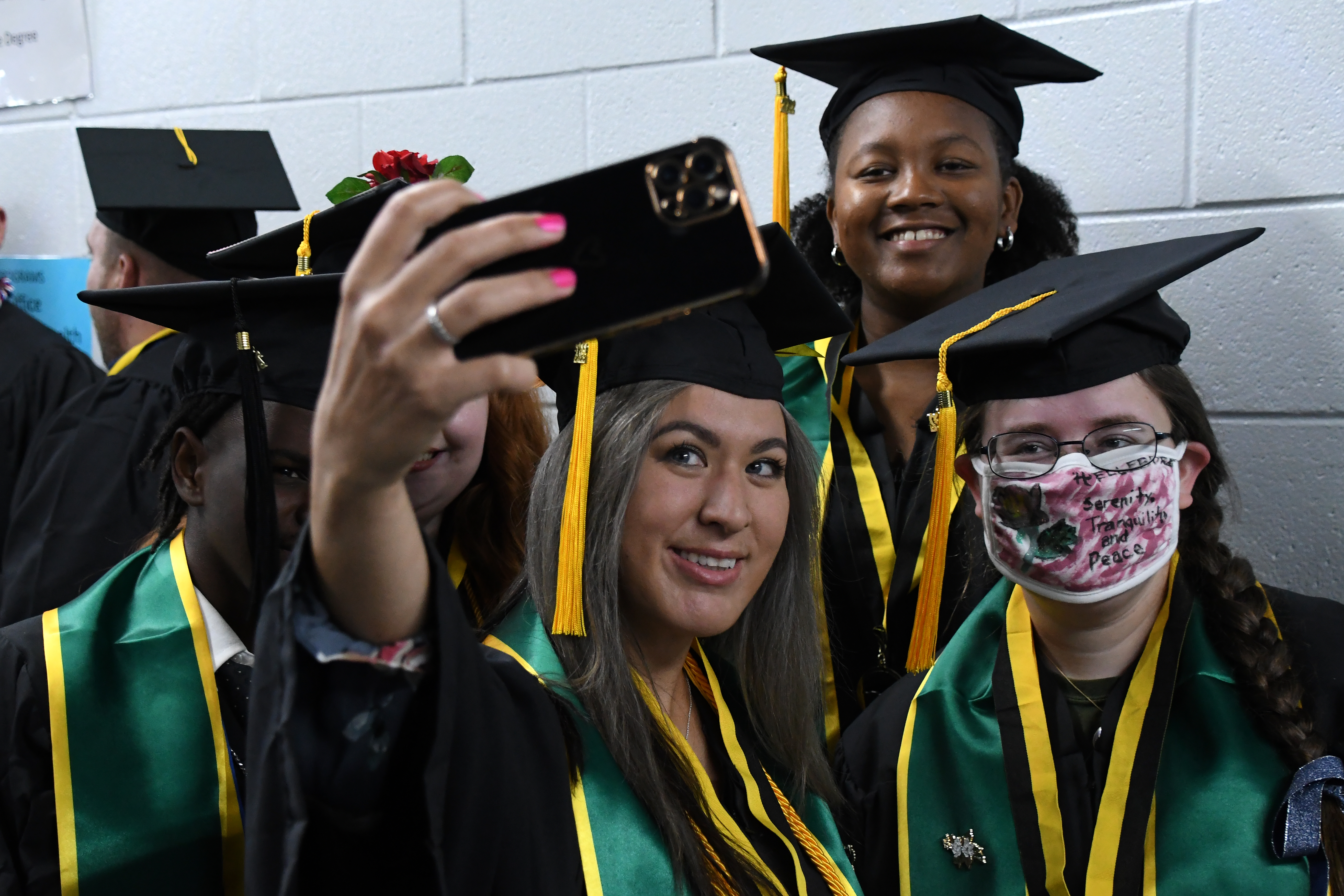 A group of graduates pose for a selfie in the hallway.